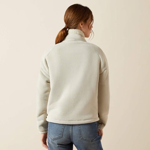 Woman wearing a light-colored fleece jacket with a neutral background