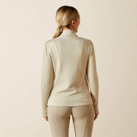 Woman wearing a beige zip-up sweater against a plain background