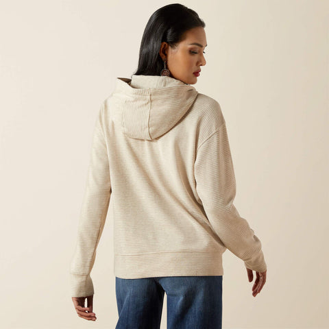 Woman wearing a beige hoodie with brown accents on a beige background