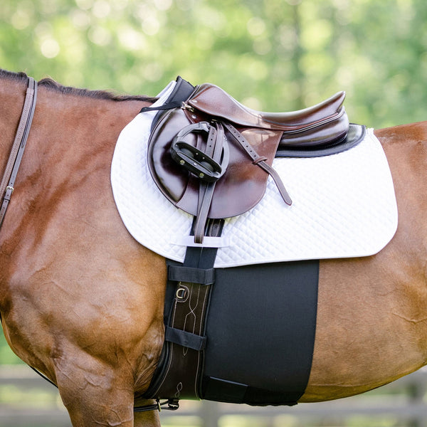 Horse with a saddle and white saddle pad on a blurred green background