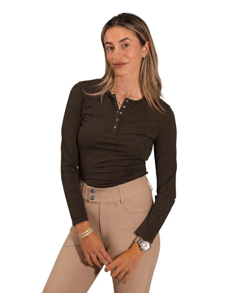 A woman modeling a dark brown ribbed long-sleeve henley top with beige riding breeches against a plain white background.