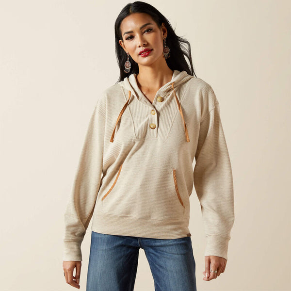 Woman wearing a beige hoodie with brown accents on a beige background