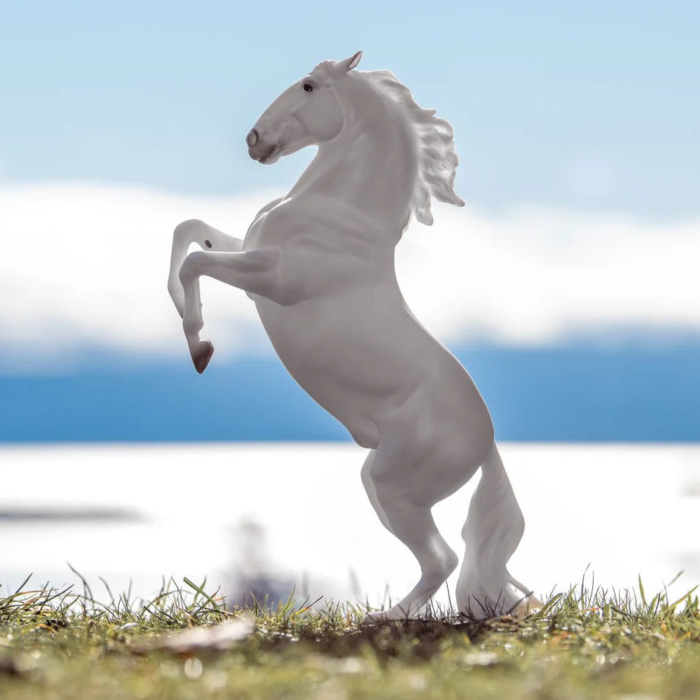 White horse figurine on grass with a blue sky background